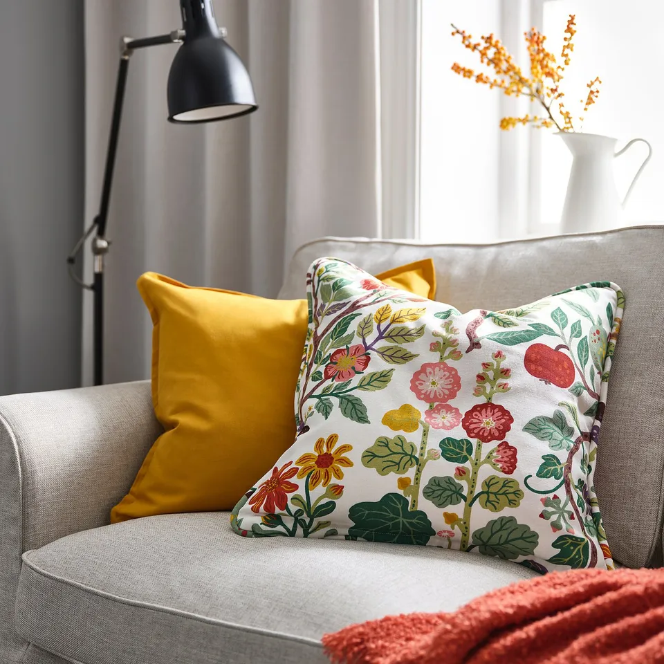 Yellow floral throw pillow on grey couch, brightening room with decor.