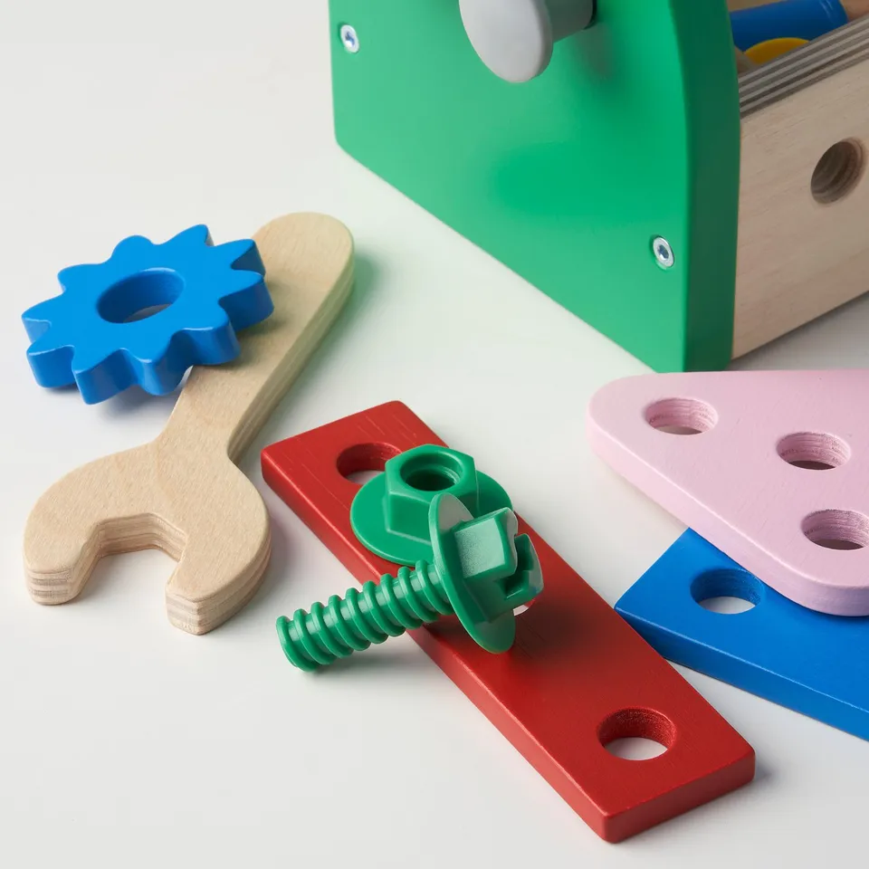 Bright childrens toolset with wooden wrench, blue gear, and bolts, in green and red plastic toolbox.