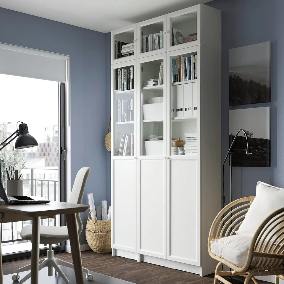 White BILLY bookcase, tall & wide, fits corner. Glass top & bottom, panels in middle. Stores books & items. Near desk & chair.