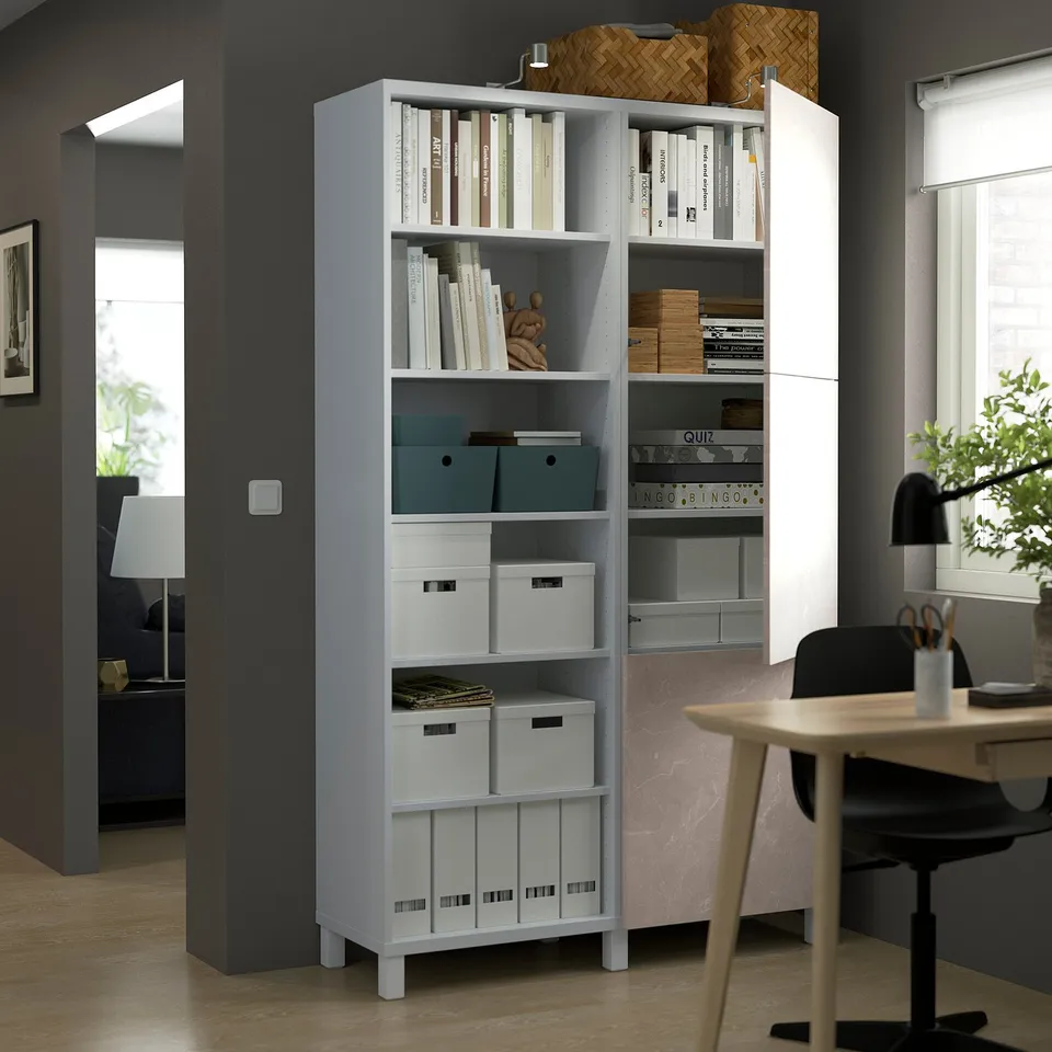 A modern home office with a white BESTÅ storage unit featuring adjustable shelves, open and closed compartments, and soft-closing doors.