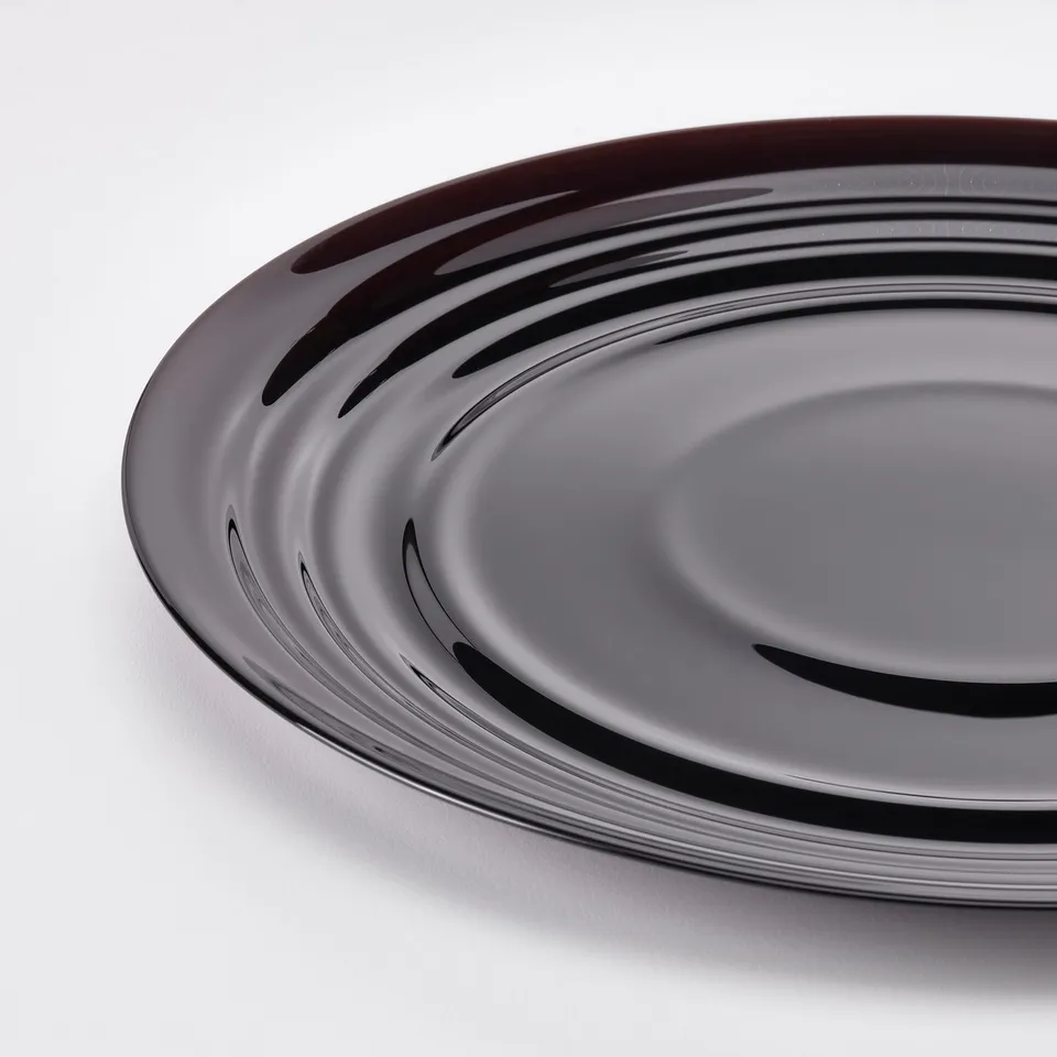 Round black glass dish with smooth, glossy finish, showing reflection and light patterns.
