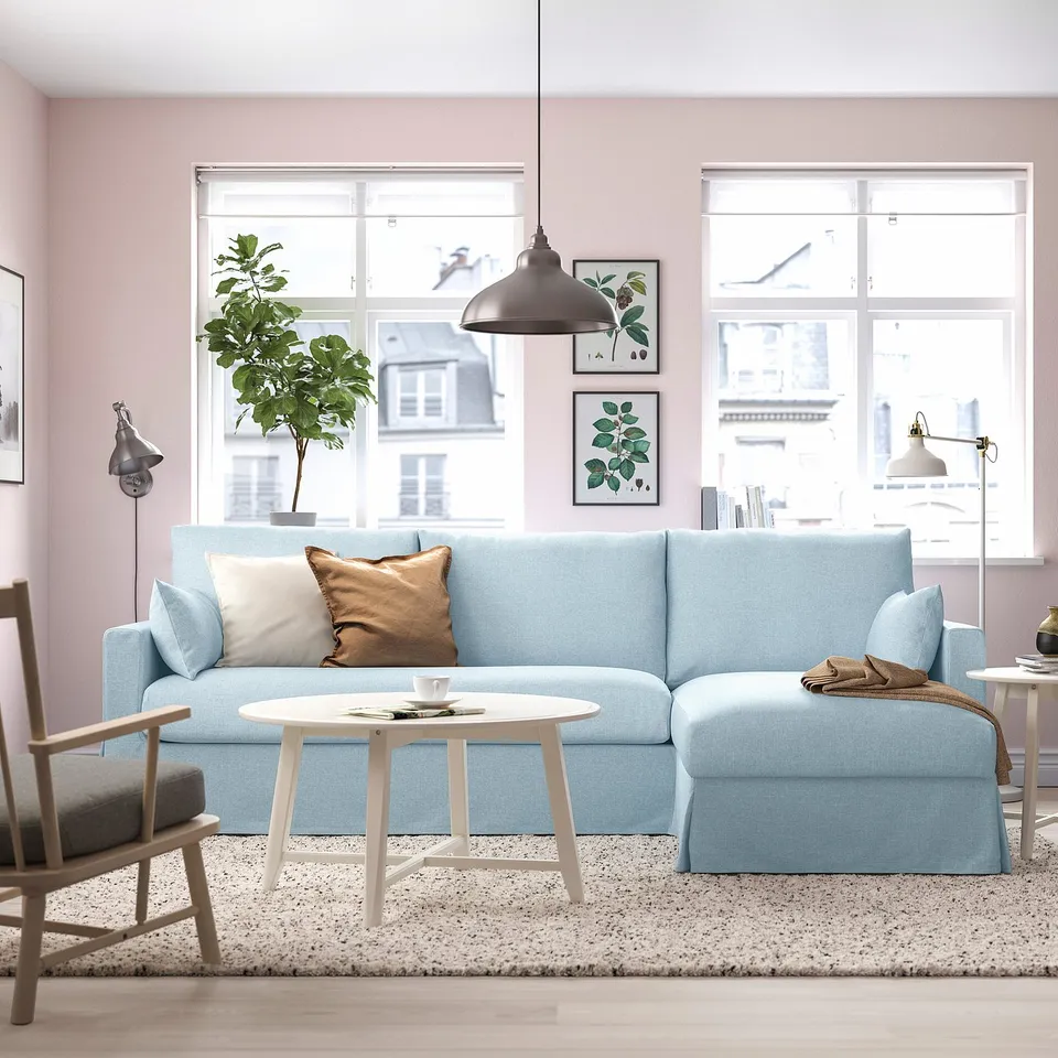 Living room with blue sofa, pink walls, large windows, and plants.