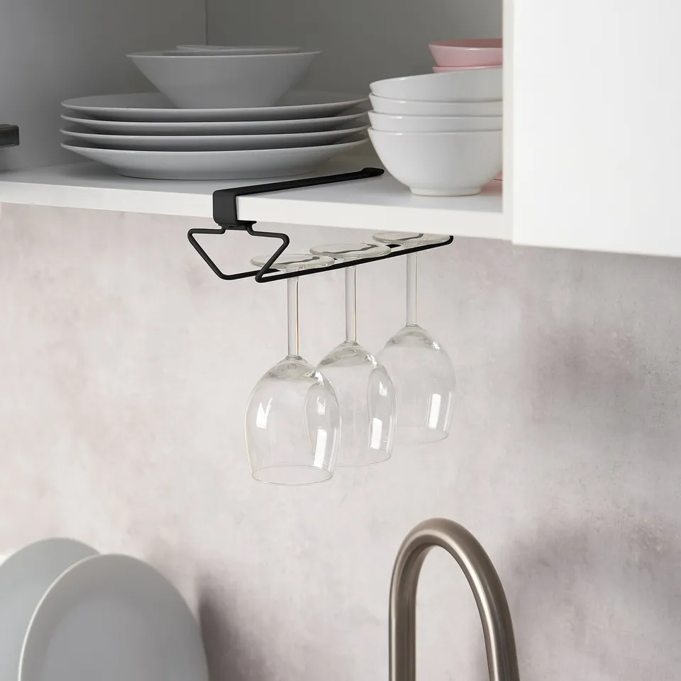 Under-shelf wine glass rack holds three glasses, saving cabinet space. Black metal design securely hangs glasses from shelf.