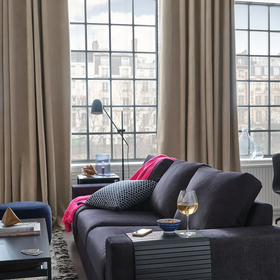Modern living room with grey sofa, wine glass, and city view.