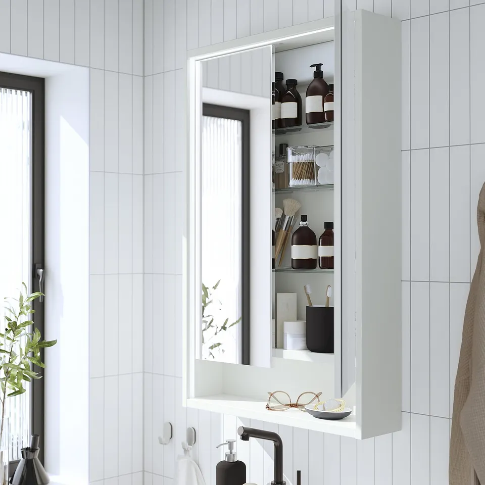 Modern bathroom mirror cabinet with built-in lighting shows neatly organised toiletries, emphasising its storage and lighting functionality.