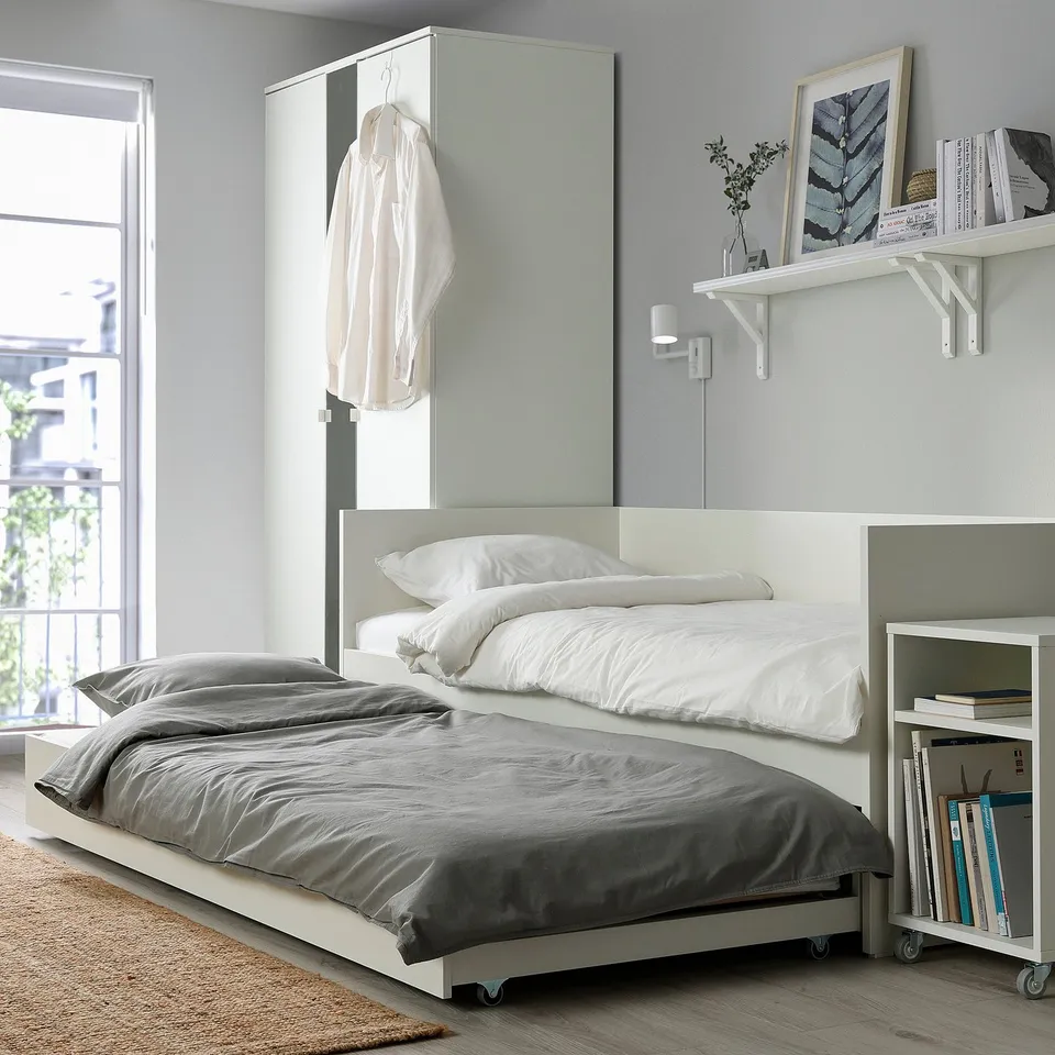 Modern bedroom with white VIHALS daybed and trundle, grey bedding, and floating shelf.