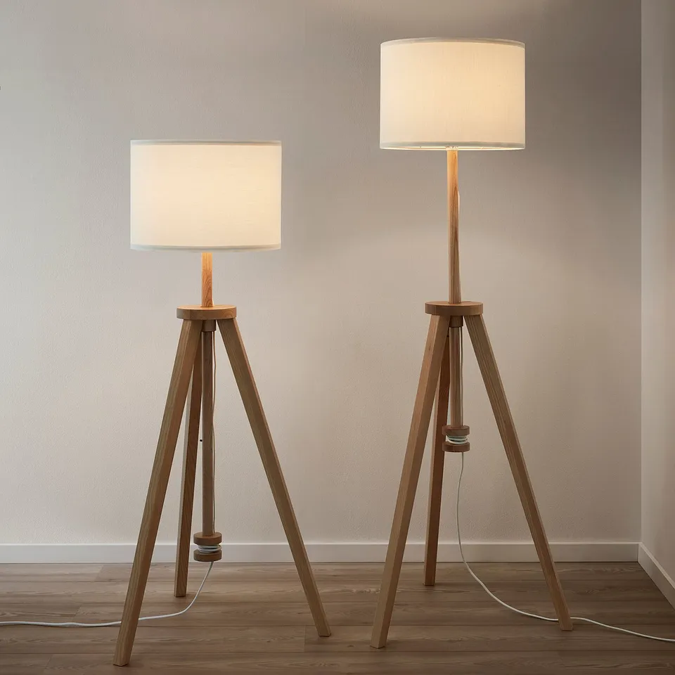 Two tripod lamps with wood bases and white shades lit, offering warm, versatile lighting.