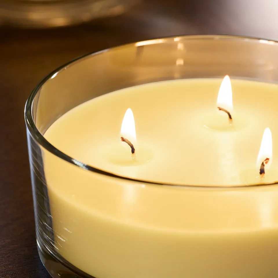 Three-lit scented candle in clear glass, emitting warm, inviting glow. High-quality, plant-based wax ensures even burn and fresh fragrance.