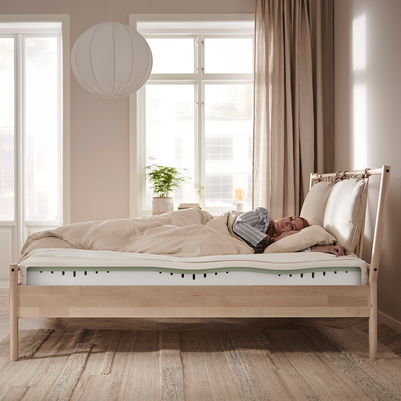 Minimalist bedroom: wooden light-colored bed with white bedding, large window, white globe pendant light.