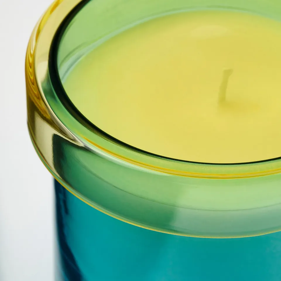 Green glass candle with yellow wax, fresh scent.