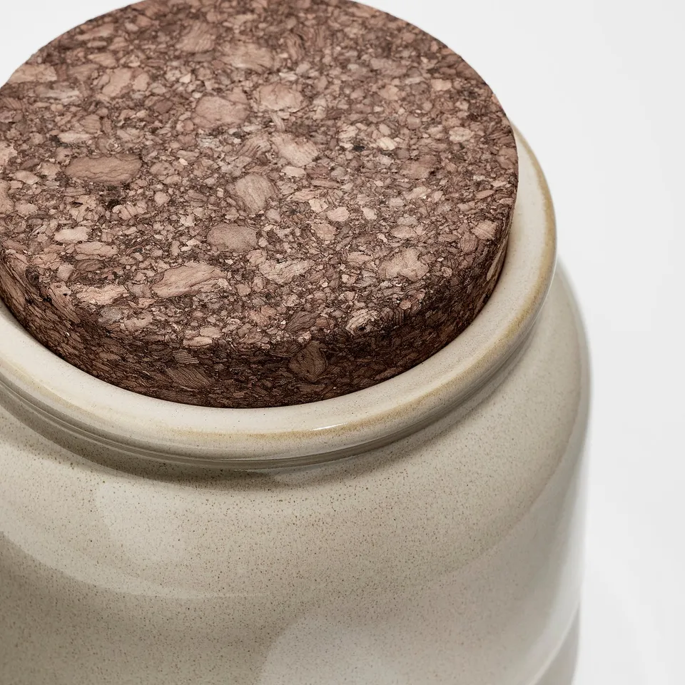 Close-up of rustic stoneware jar with glazed finish and cork lid, showcasing high-quality craftsmanship and natural texture.