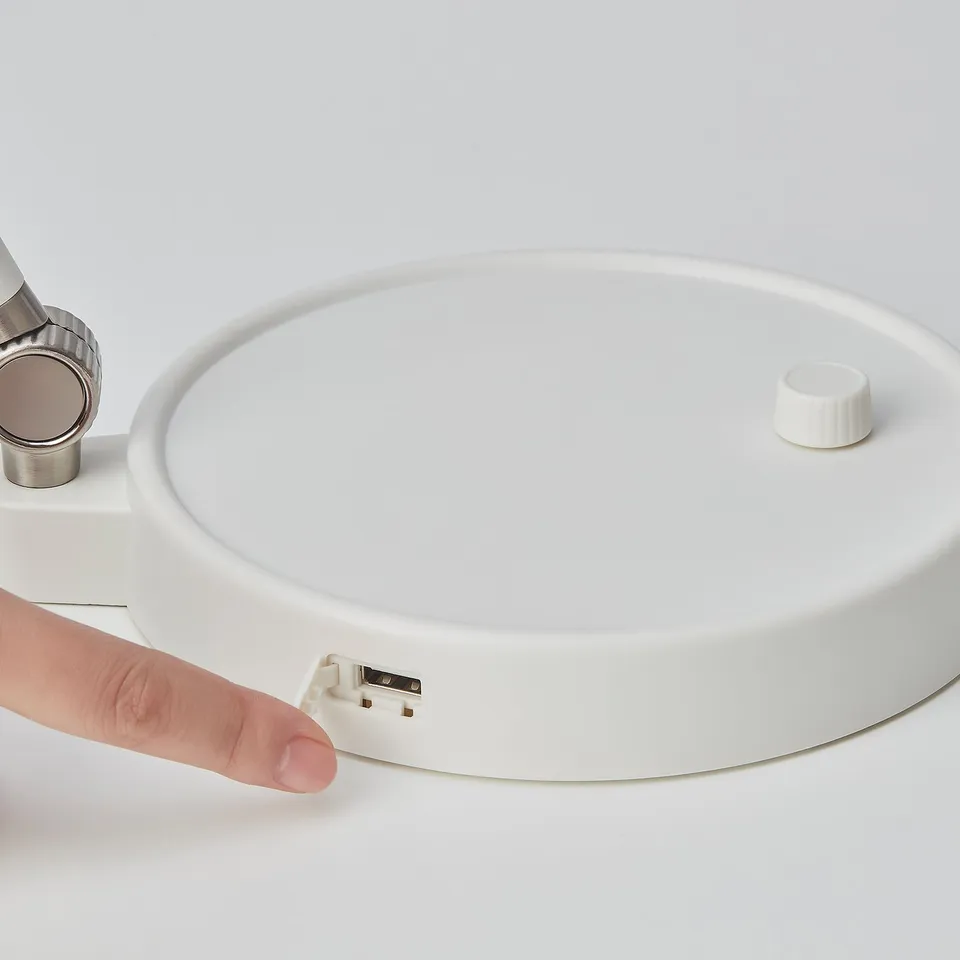 Hand adjusting modern, sleek white ORSALA lamp with usb port and adjustable brightness, showcasing its quality and functionality.