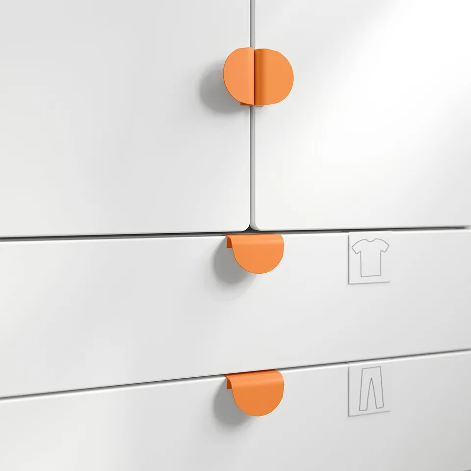 Three white cabinet drawers with rounded orange handles, aligned vertically. Top drawer slightly open. Simplistic design, easy to grip handles.