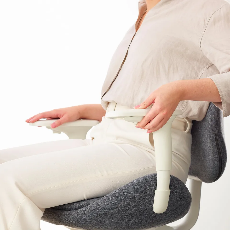 Person adjusting armrests of ergonomic office chair, ensuring comfort and support.