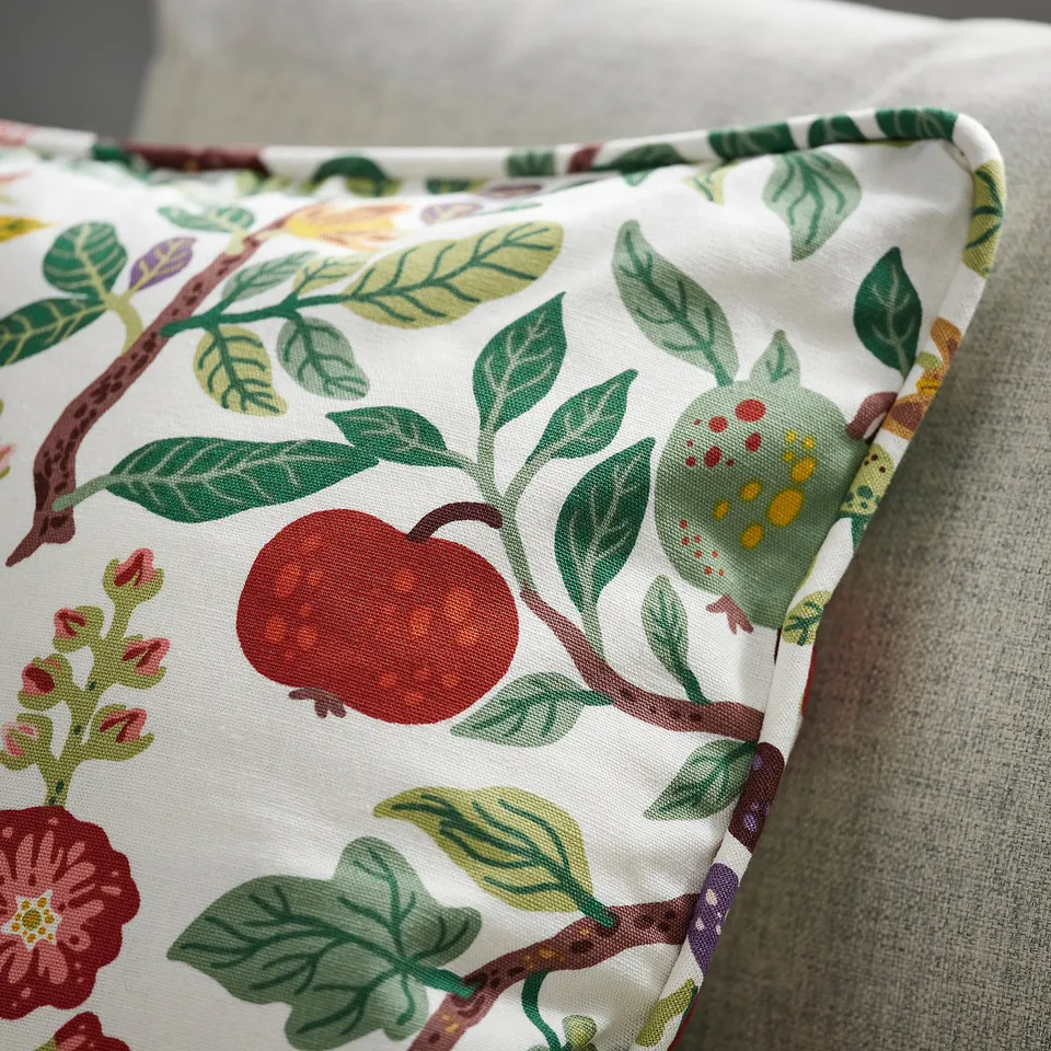 Face of a cushion cover with vibrant, detailed apple and floral patterns. Quality fabric with visible stitching.