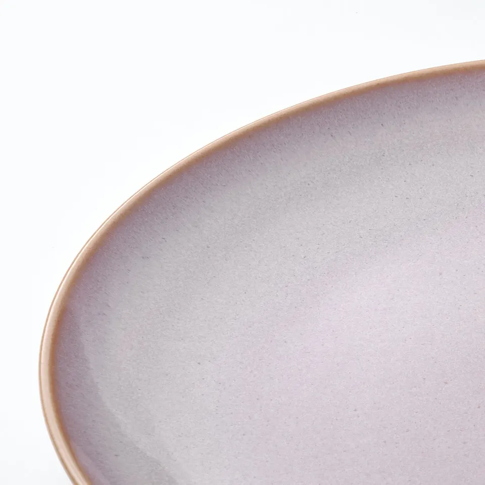 Closeup of a smooth, round dish with a light lavender matte finish. Edge curves gently inward.