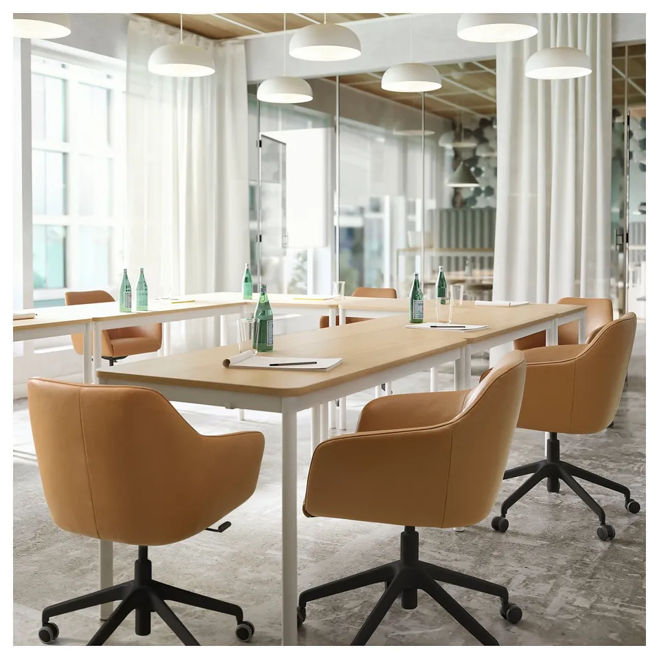 Modern office meeting room with TOSSBERG chairs in brown leather, large wooden table, and white pendant lights.