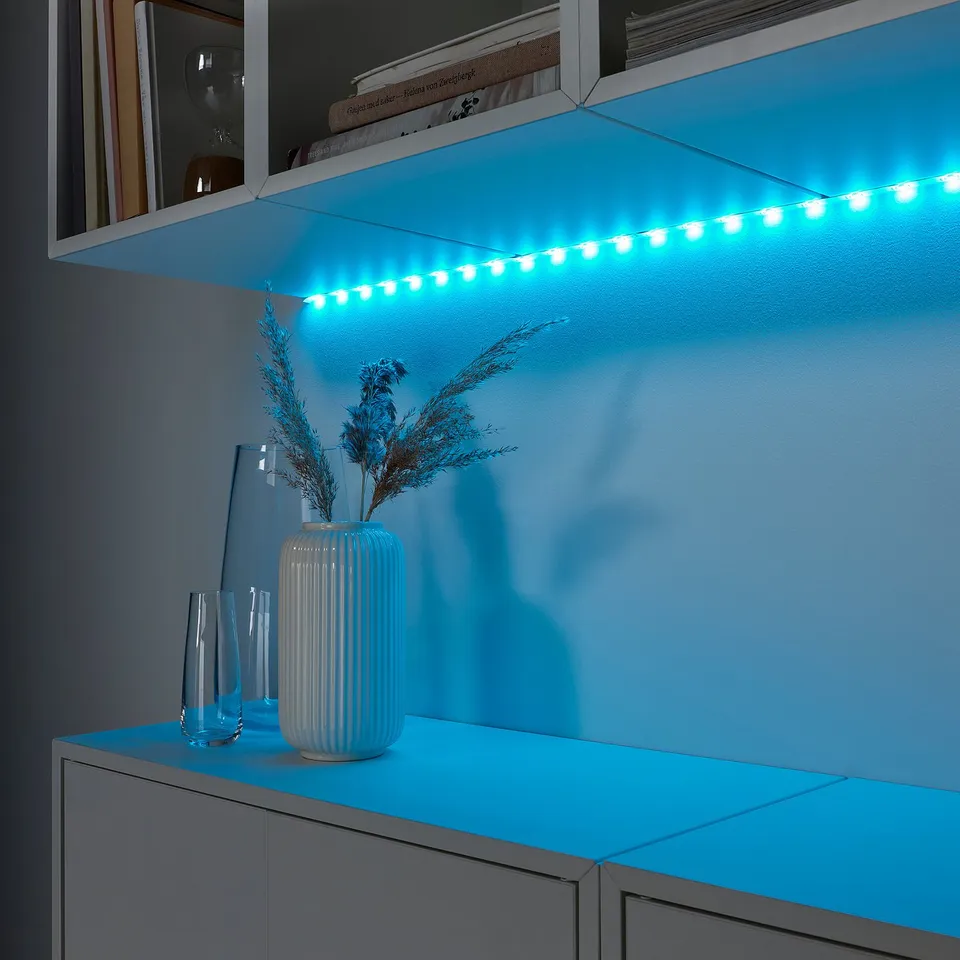 Led shelf with blue strips, illuminating white vase and dried grasses, color-changing.