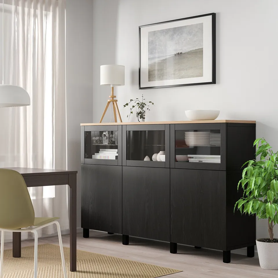 Modern living room with BESTÅ black sideboard, green chair, and hanging picture.