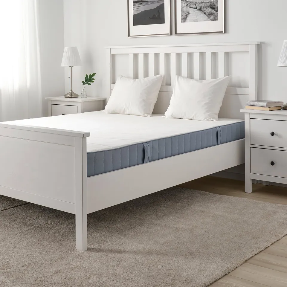 Minimalist white bedroom with VESTMARKA mattress, nightstands, and grey rug.