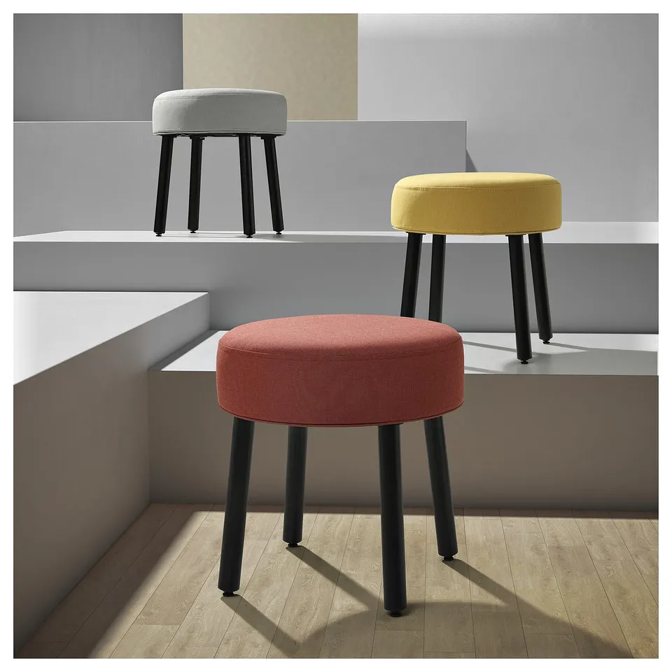 Three colourful round stools in red, yellow, grey with black legs; modern fabric design.