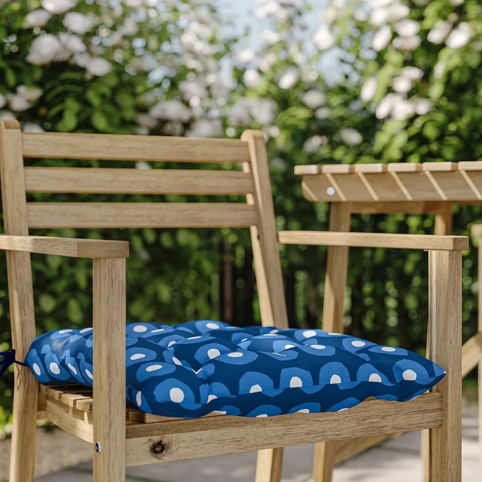 Two wooden chairs with blue and white patterned cushions, placed outdoors.