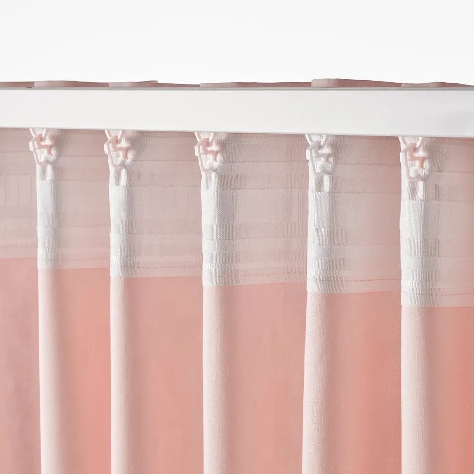 Light pink curtains hang neatly, featuring subtle texture and white accents, attached with hooks.