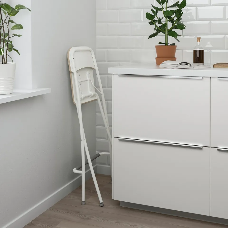 Foldable white bar stool with footrest in modern kitchen.