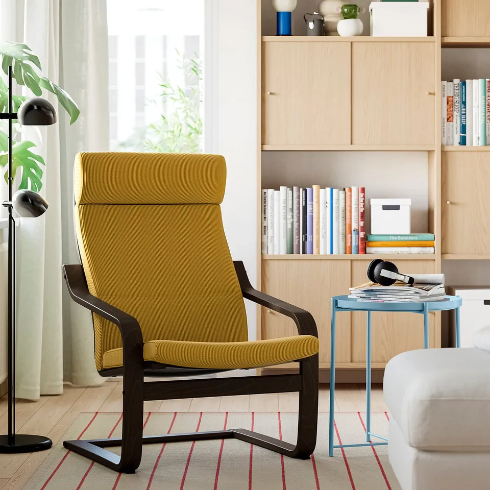 Yellow POÄNG recliner in cosy living space with wooden frame.
