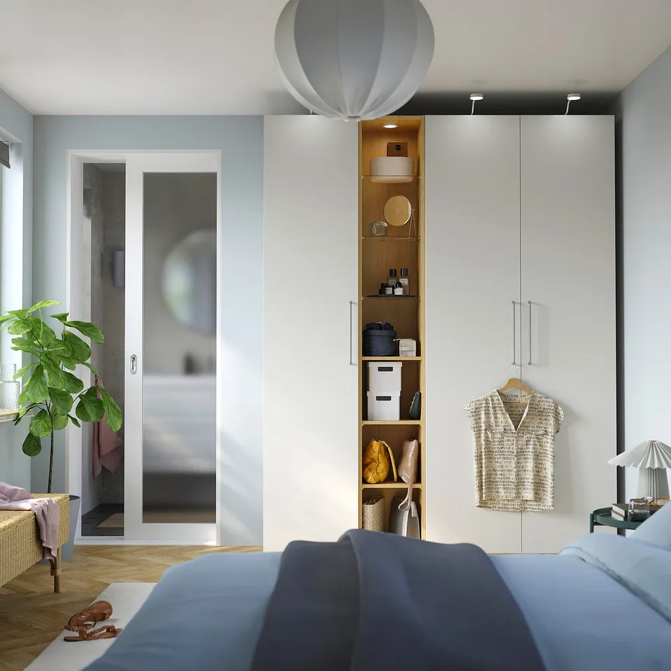 Modern bedroom with blue bed, narrow PAX wardrobe, and plant.