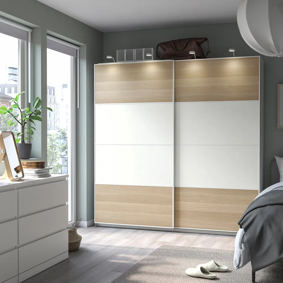Modern bedroom with MEHAMN white and wood sliding wardrobe, grey walls, wooden floor, and large window.
