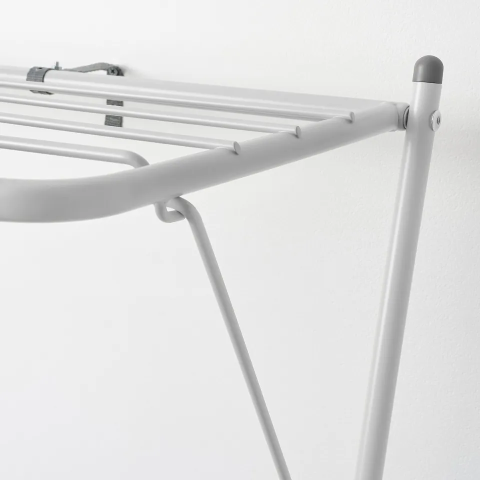 A close-up of a robust, white metal clothes drying rack, showing its sturdy frame, multiple horizontal bars, and supportive legs.
