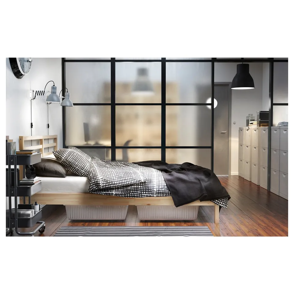 Modern bedroom with a TARVA wooden bed in natural pine. Black & white bedding, large window, and storage units.