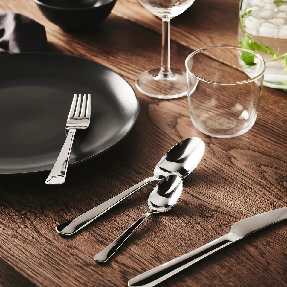 Table setting with metallic cutlery, plates, and glasses.