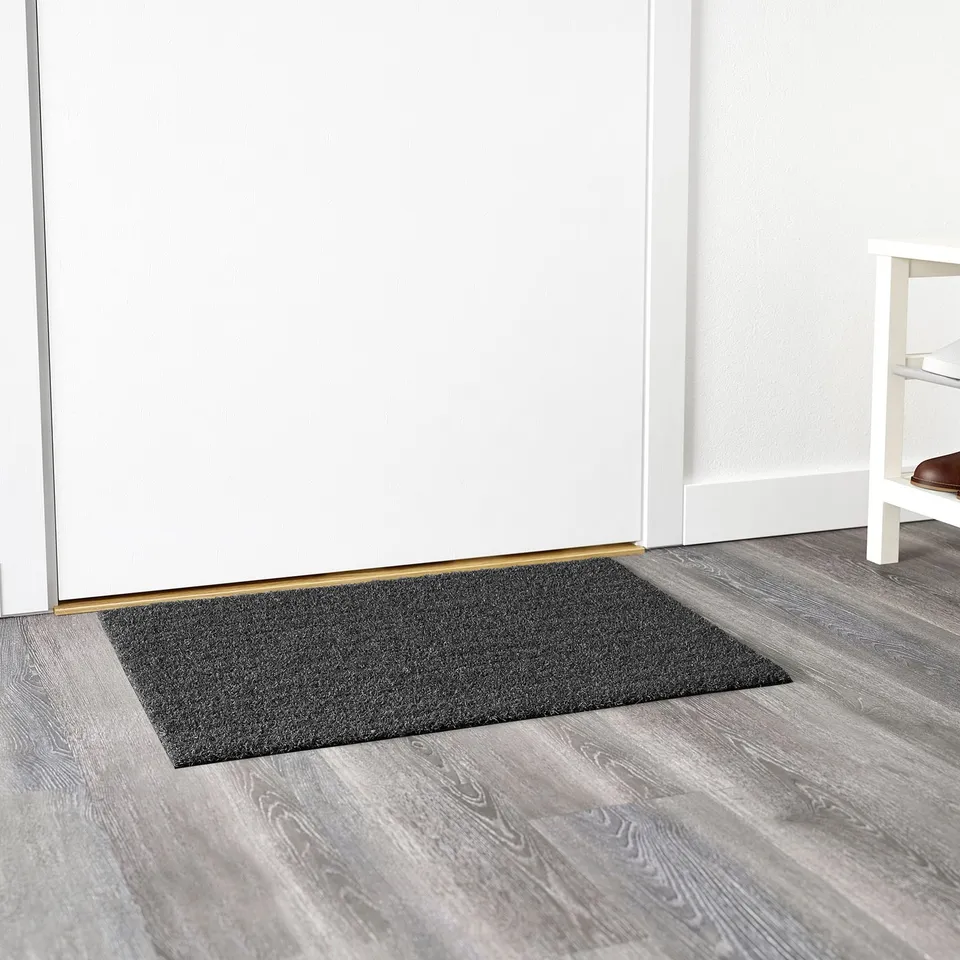 Rectangular grey doormat placed at entrance, backed for stability, suitable for outdoor use.