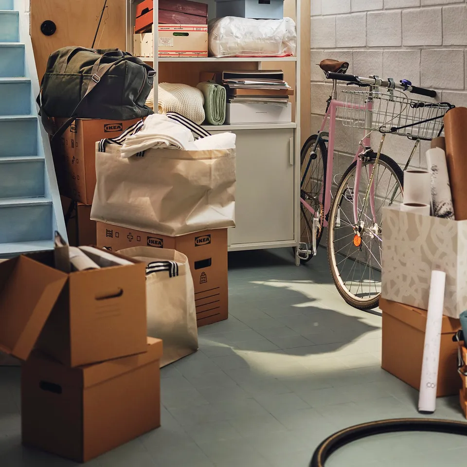 Cardboard boxes, including PAPPIS, in storage with bike and bags.