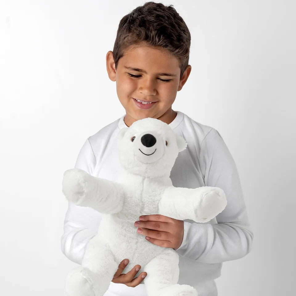 Boy holding a white SNUTTIG teddy bear, smiling.