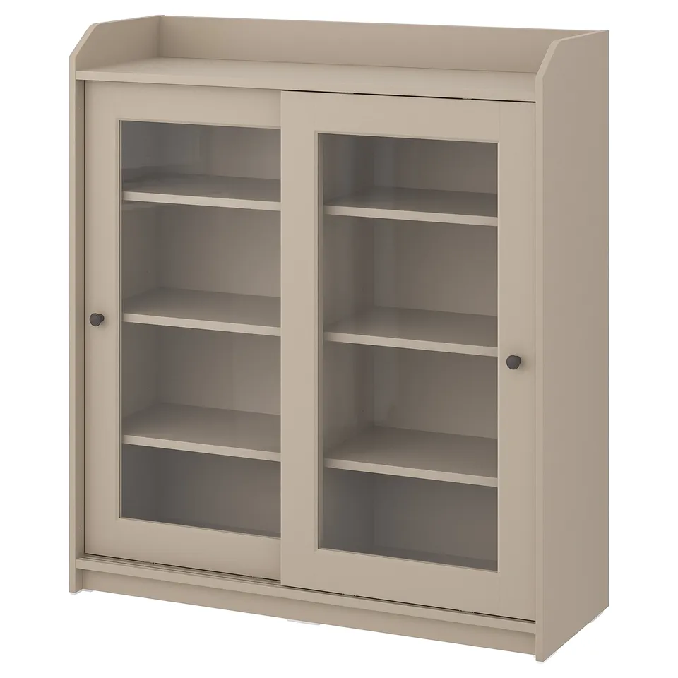 Beige HAUGA glass-door cabinet, sliding doors, wooden structure, rectangular shape, three shelves.