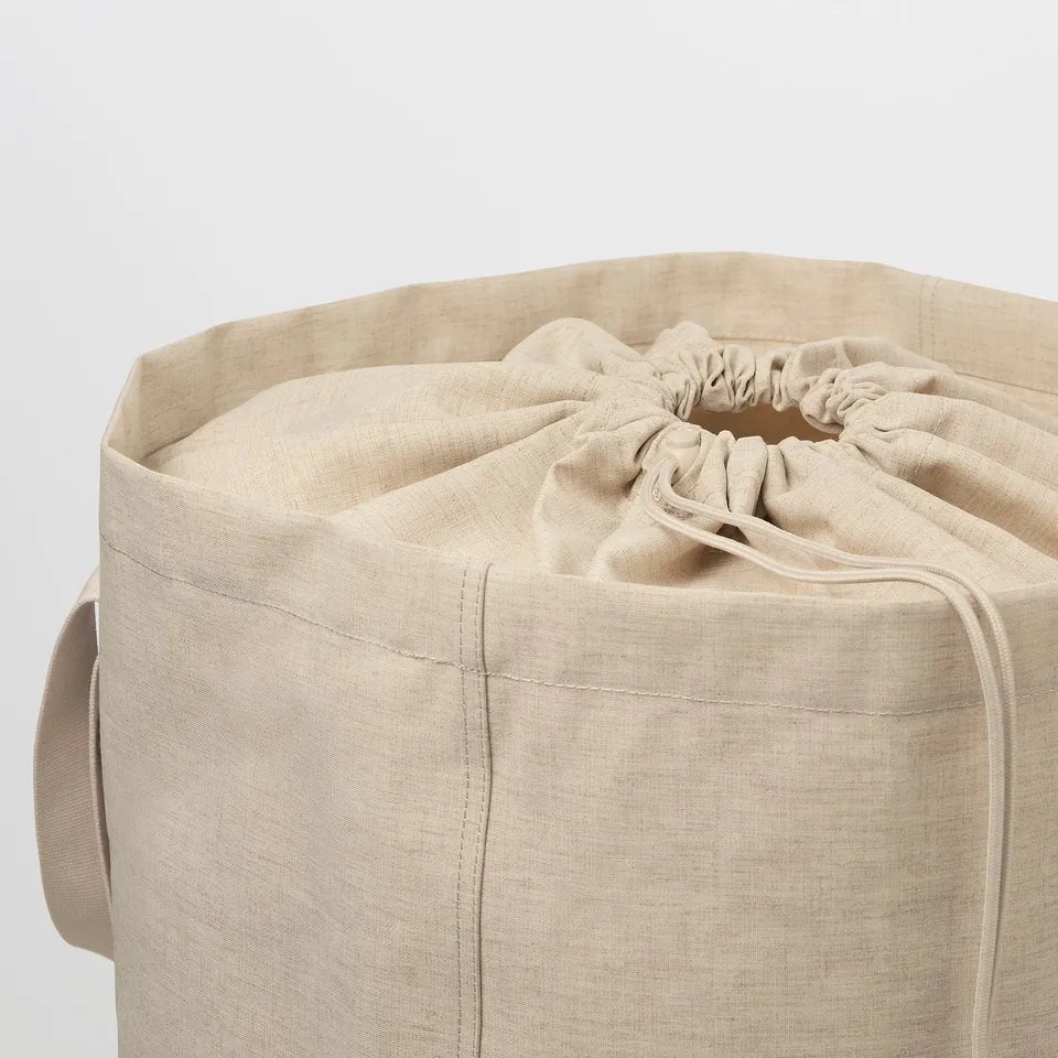 Large beige laundry tote bag with drawstring closure, beige handles, thick fabric, drawstring cinched top.
