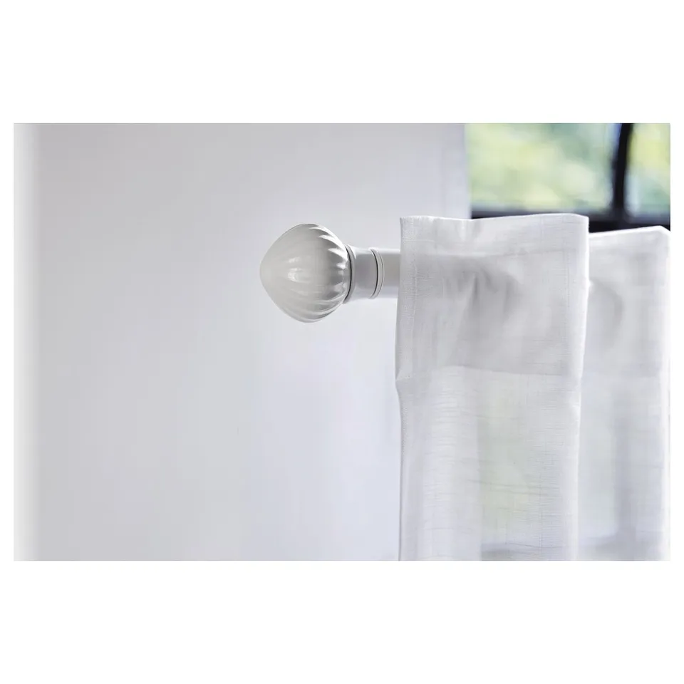 A white ceramic finial attached to a curtain rod. The finial is elegant and ball-shaped, enhancing a minimalist decor.