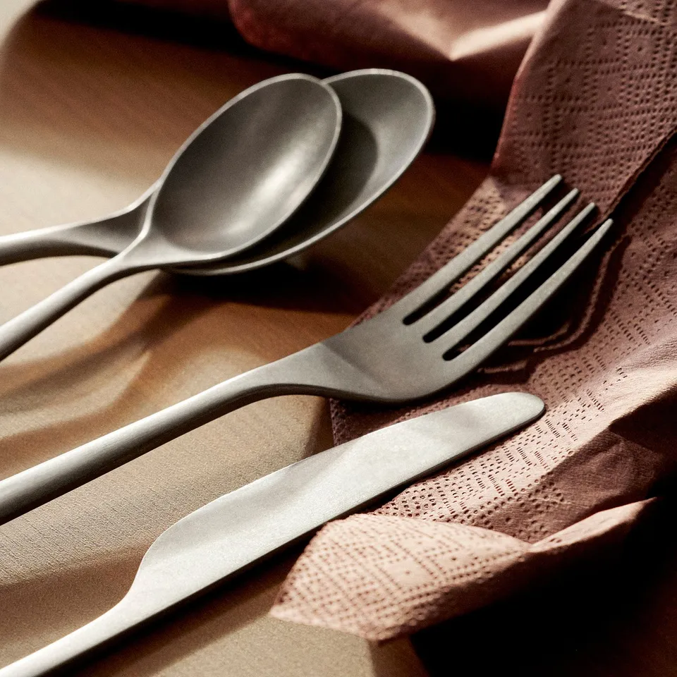 Stainless steel cutlery on cloth, elegant design.