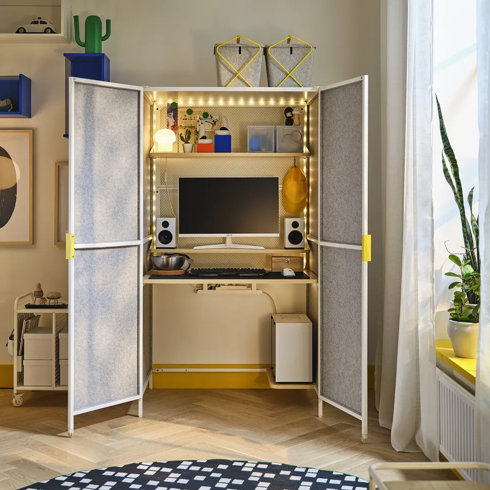 A modern gaming station with a desk inside, featuring storage shelves and led lights, with a gaming chair and monitor visible.