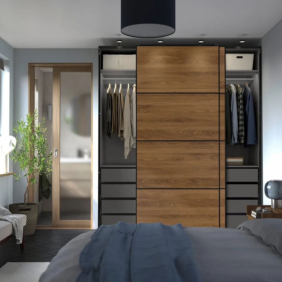 Modern wardrobe with sliding doors, hanging clothes, and drawers, anchored to wall for safety.
