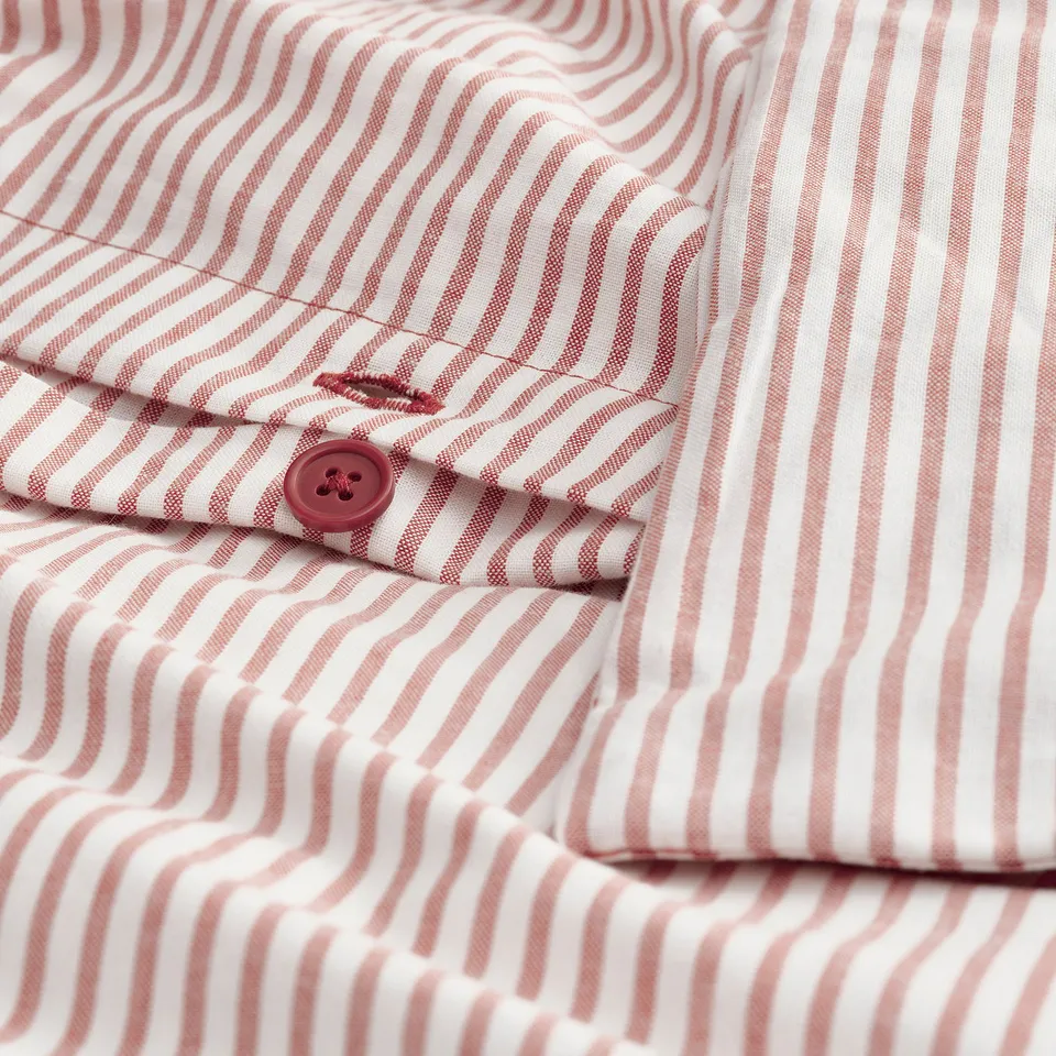 Close-up of striped shirt with a red button.